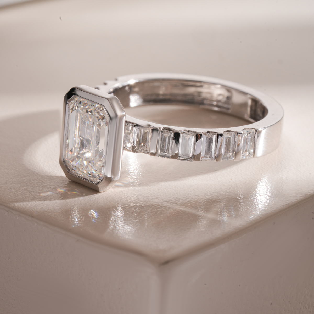 White gold engagement ring close-up with emerald-cut center and baguette band stones