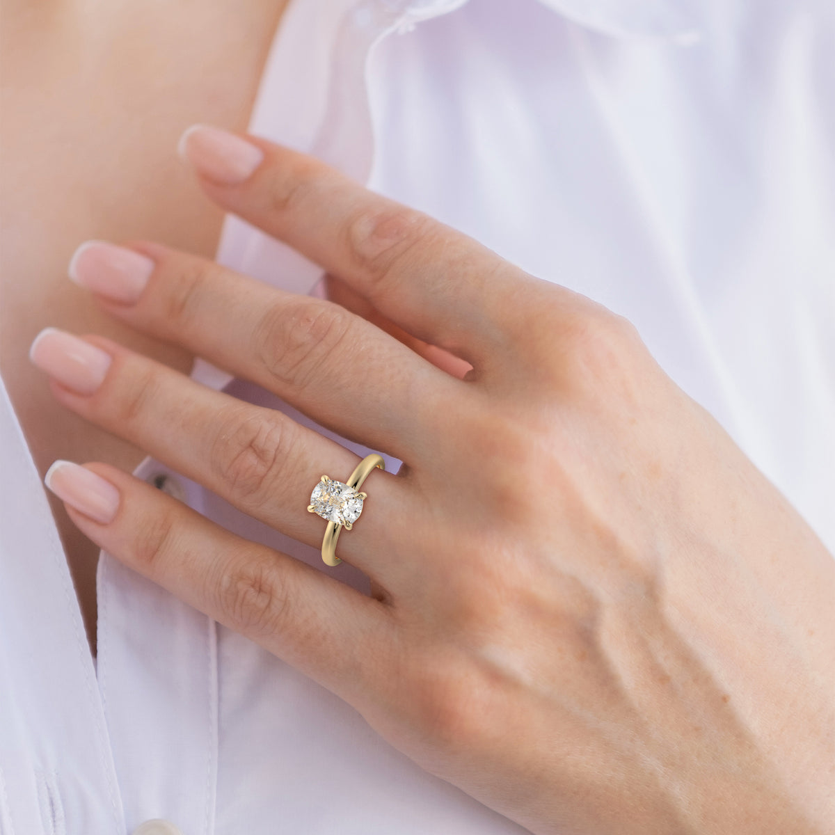 Yellow gold cushion solitaire ring with cushion diamond, shown on hand