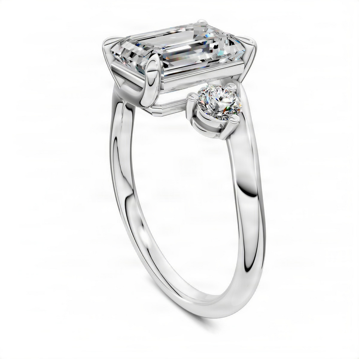 Three-stone bypass ring in white metal with emerald-cut center and round side stone, side view